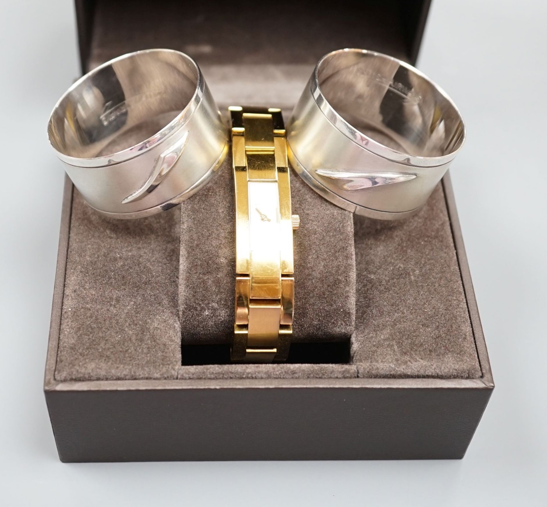 A modern pair of silver 'Concorde' napkin rings, together with a lady's gilded stainless steel Gucci quartz wrist watch with box, no papers.